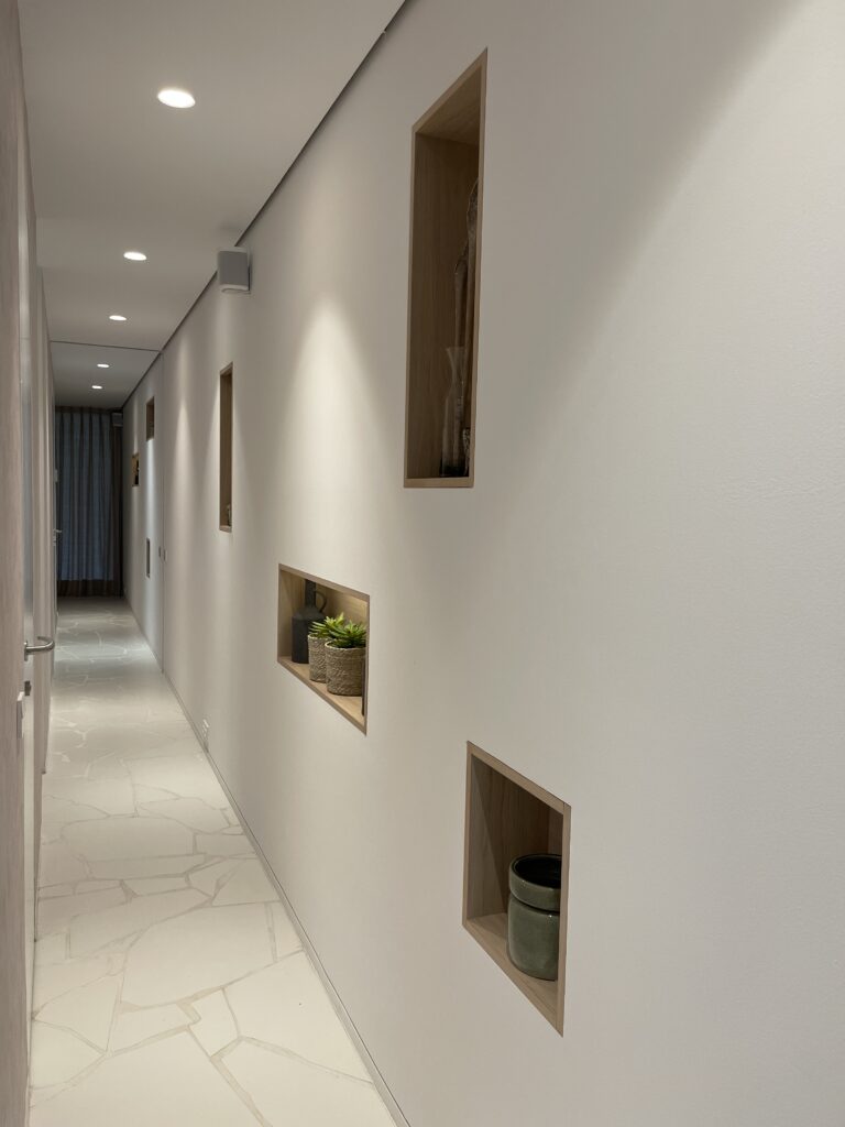 Pasillo con muebles de estantes empotrados a pared con iluminación.